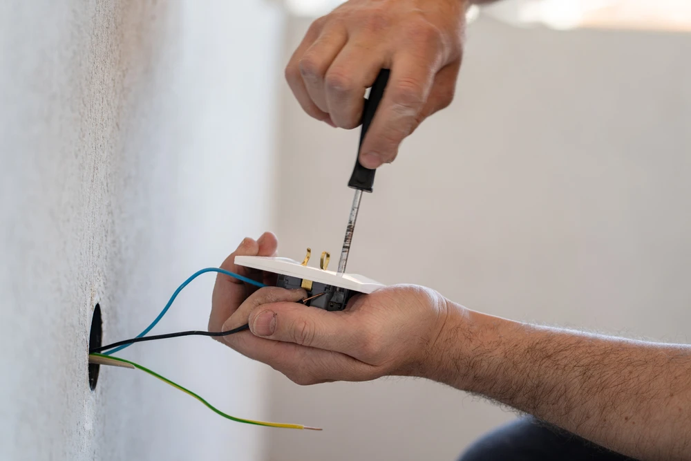 Électricien installant un interrupteur mural dans un intérieur résidentiel