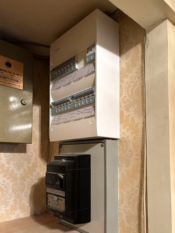 Électricien professionnel en uniforme bleu et casquette travaillant sur tableau électrique domestique ouvert