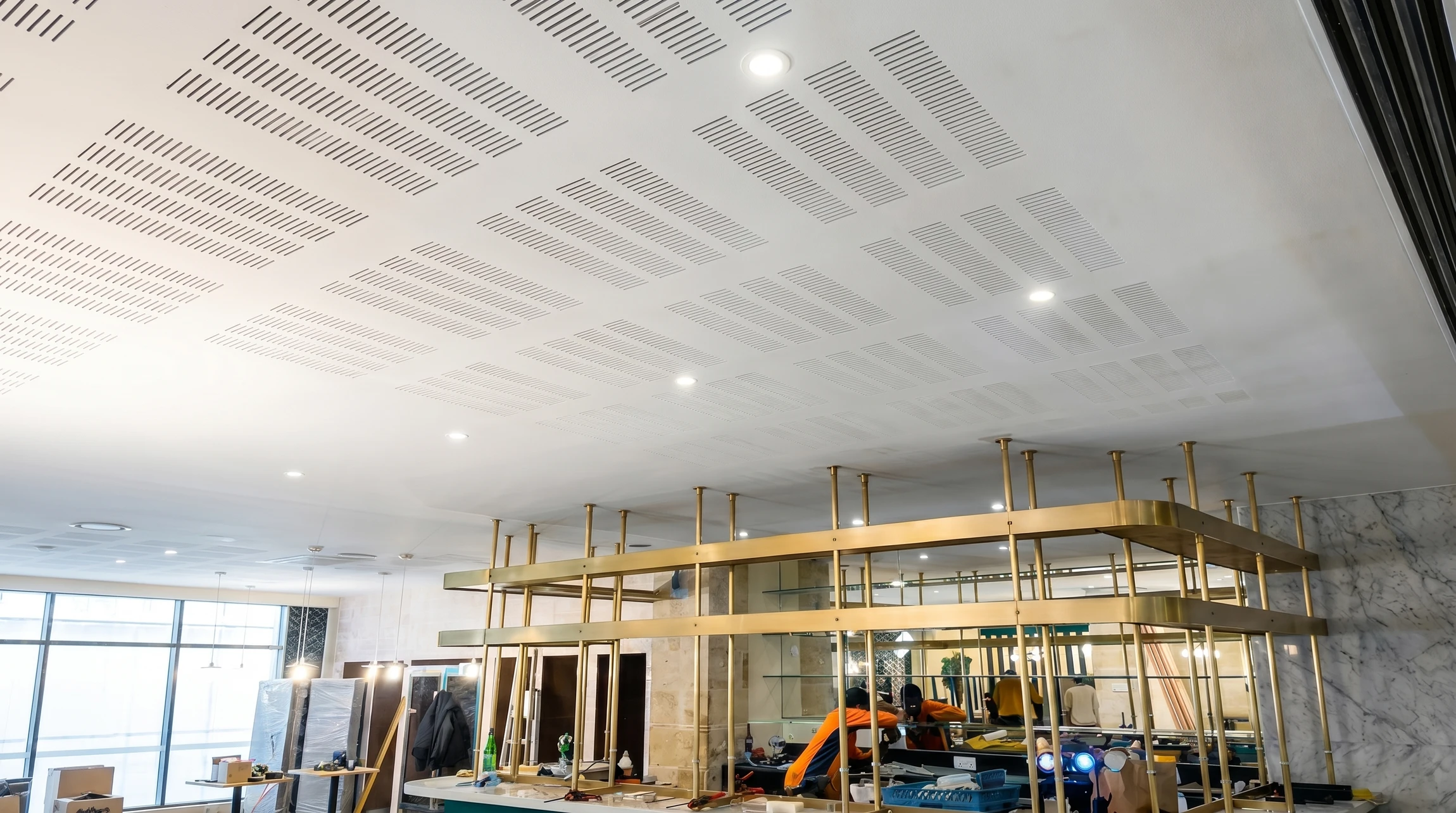 Électricien en tenue bleue effectuant des mesures électriques sur installation murale avec multimètre numérique orange