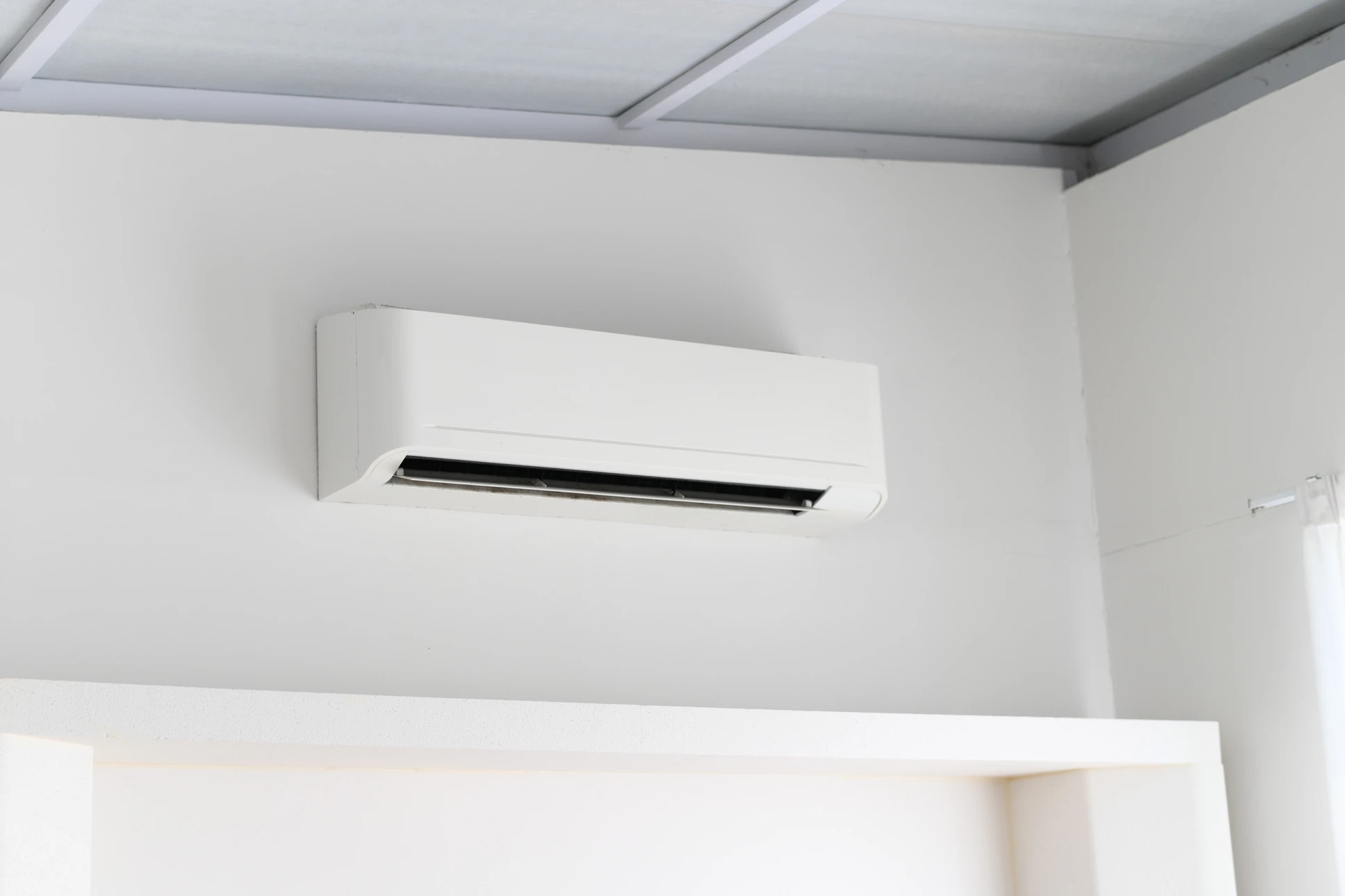 Technicien en uniform travaillant sur l'entretien d'une unité intérieure de climatisation fixée au plafond