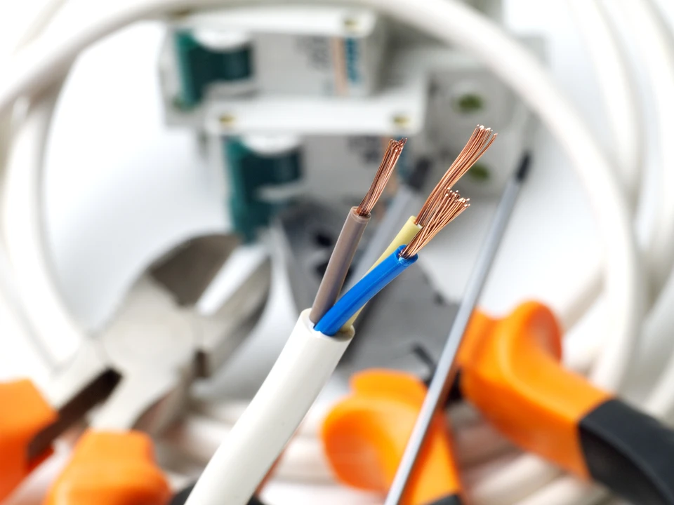 un électricien mâle travaille dans un tableau de contact avec un câble de connexion électrique, connecte l'équipement avec des outils, le concept de travail complexe, l'espace pour le texte