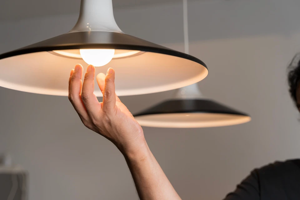 Un électricien en salopette, concentré sur le travail dans le standard avec fusibles, en utilisant une tablette