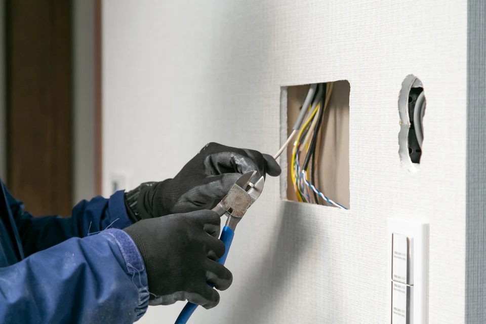 Sc&egrave;ne d'int&eacute;rieur montrant une prise &eacute;lectrique murale d&eacute;faillante avec flammes visibles et fum&eacute;e